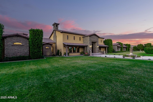 view of front facade featuring stone siding, a tiled roof, a front lawn, and stucco siding