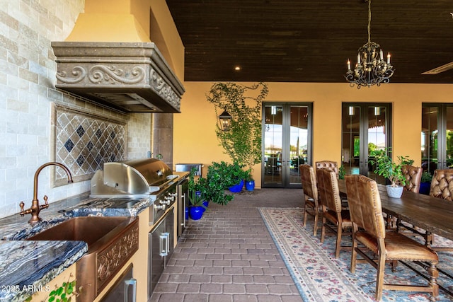 kitchen featuring tasteful backsplash, dark countertops, custom exhaust hood, french doors, and a chandelier