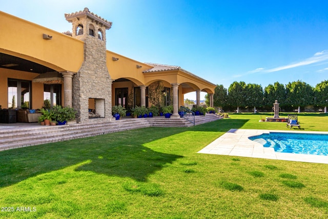 exterior space with a yard, an outdoor stone fireplace, a patio area, and stucco siding