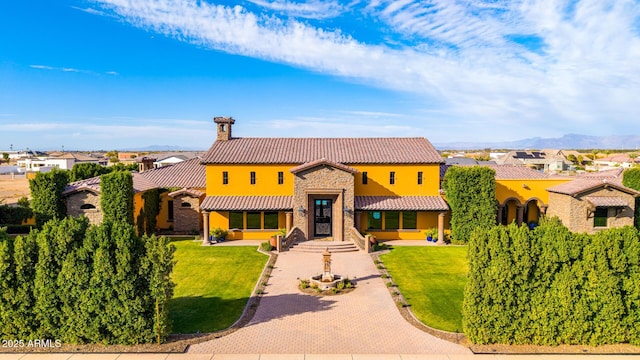 mediterranean / spanish house with a tiled roof, stone siding, decorative driveway, and a front yard