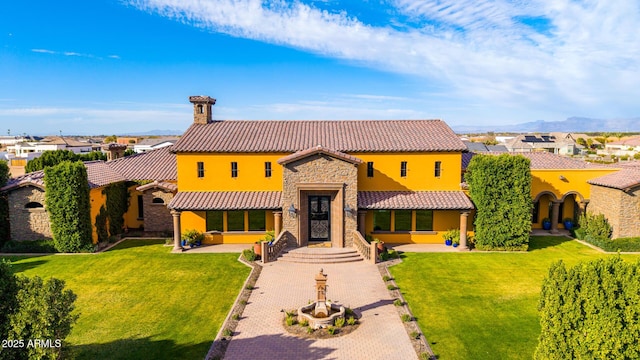 mediterranean / spanish house featuring stone siding, a tile roof, a residential view, and a front yard