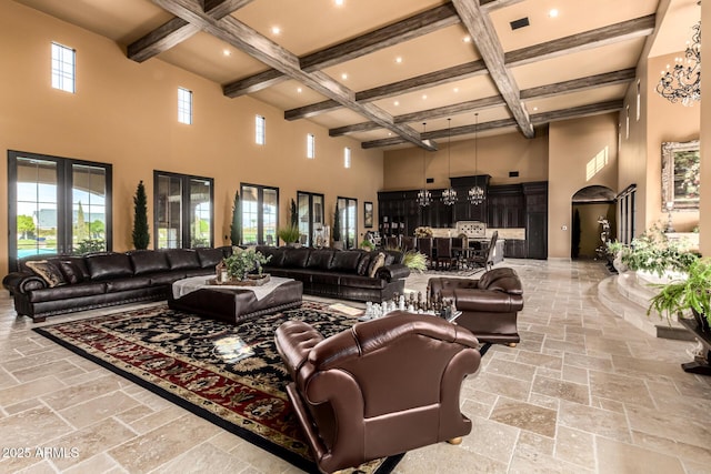 living room featuring stone tile floors, a high ceiling, an inviting chandelier, coffered ceiling, and beamed ceiling