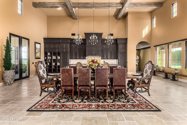 dining room with stone tile flooring, beamed ceiling, baseboards, and an inviting chandelier