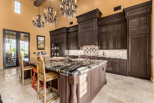 kitchen with a large island, stone tile flooring, decorative light fixtures, and dark brown cabinetry