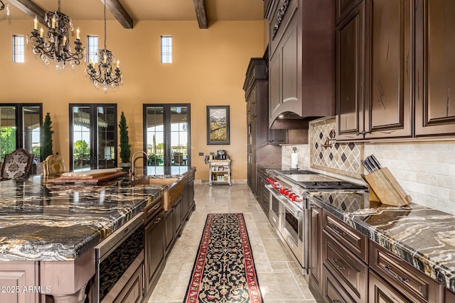 kitchen with range with two ovens, french doors, decorative backsplash, beamed ceiling, and dark stone countertops