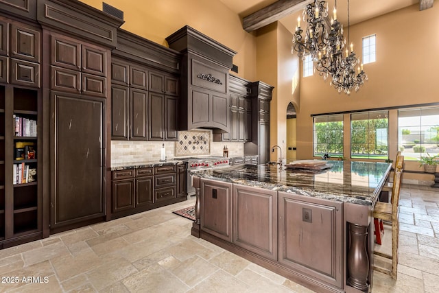 kitchen with high end stove, dark brown cabinetry, a kitchen breakfast bar, a large island, and stone tile flooring