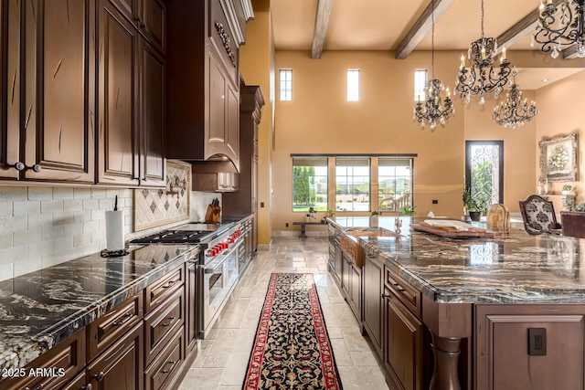 kitchen with dark stone counters, range with two ovens, stone tile flooring, dark brown cabinets, and a sink