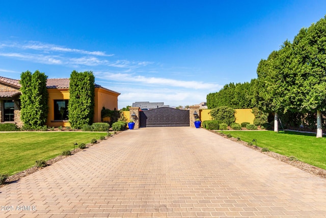 view of front facade with a tile roof, a front lawn, decorative driveway, and stucco siding