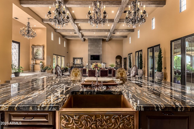 kitchen with dark stone counters, coffered ceiling, a high ceiling, and an inviting chandelier