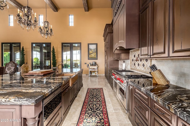 kitchen with range with two ovens, french doors, decorative backsplash, dark stone countertops, and beamed ceiling