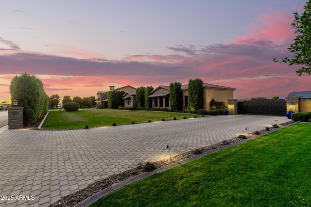 view of front of property with decorative driveway, a gate, and a yard