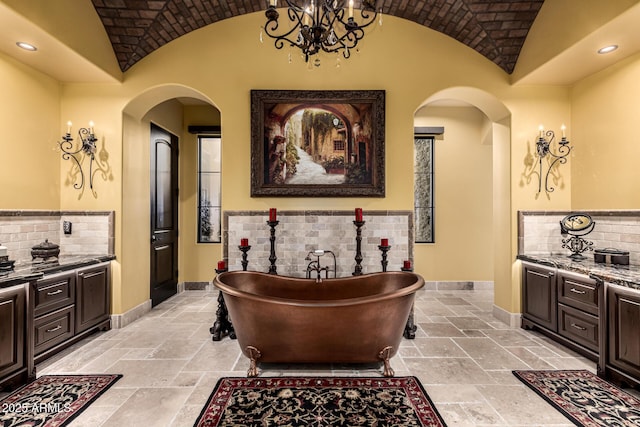 interior space with lofted ceiling, stone tile floors, arched walkways, and baseboards