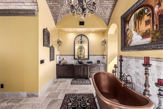 bar featuring baseboards, brick ceiling, backsplash, stone tile flooring, and an inviting chandelier