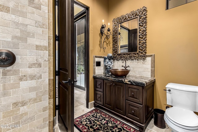 bathroom featuring toilet, tasteful backsplash, and vanity