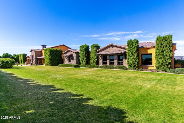 mediterranean / spanish-style house with stone siding, a front yard, a tile roof, and stucco siding