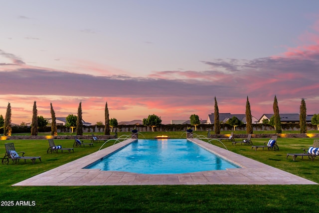 pool at dusk featuring a yard, a patio, a residential view, and an outdoor pool