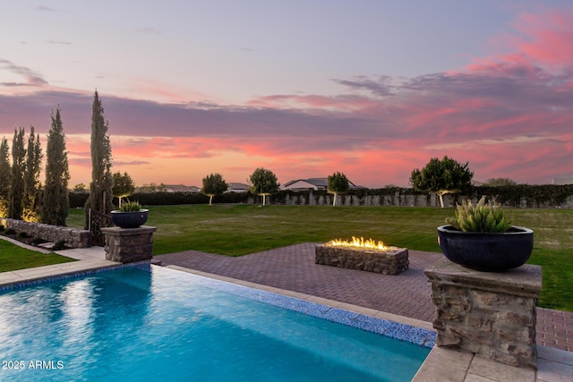 pool featuring a patio area, a yard, and a fire pit