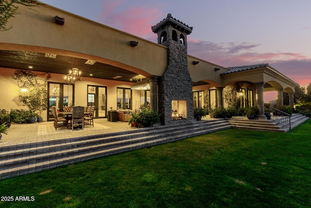 back of property with a yard, a patio, and stucco siding