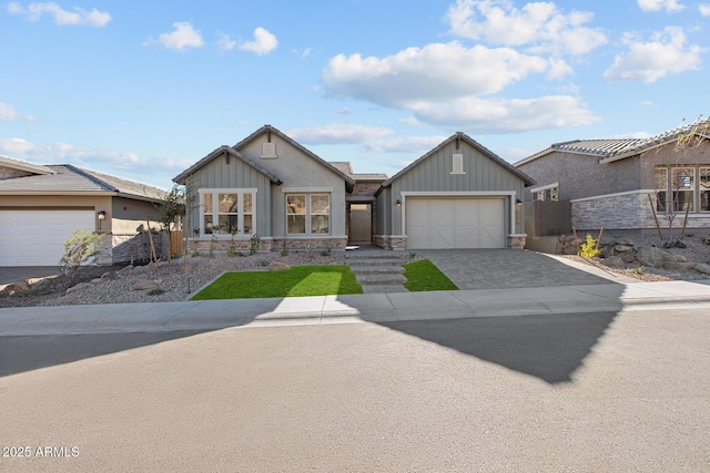 view of front of property featuring a garage, fence, stone siding, decorative driveway, and board and batten siding