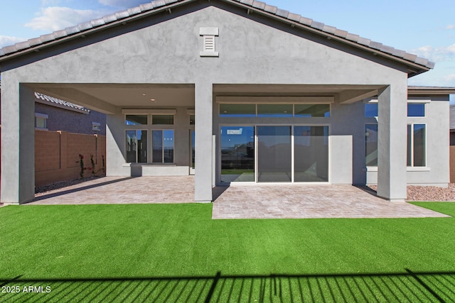 rear view of house featuring a patio, a yard, and stucco siding