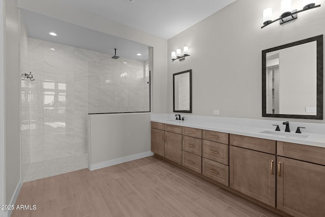 full bath featuring double vanity, a walk in shower, a sink, and wood finish floors