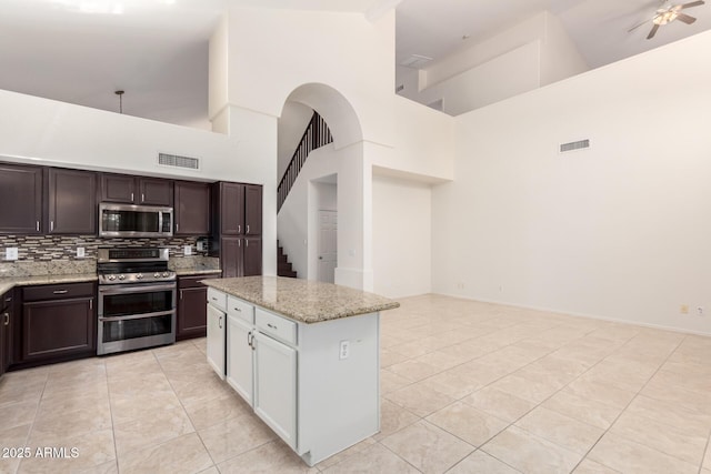 2741 E San Tan St, Chandler, AZ 85225 - kitchen featuring appliances with stainless steel finishes, a high ceiling, light tile patterned flooring, tasteful backsplash, and light stone countertops