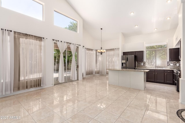 2741 E San Tan St, Chandler, AZ 85225 - kitchen featuring appliances with stainless steel finishes, a kitchen island, high vaulted ceiling, a chandelier, and decorative backsplash
