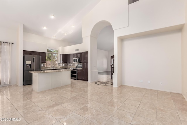 2741 E San Tan St, Chandler, AZ 85225 - kitchen with stainless steel appliances, high vaulted ceiling, dark brown cabinetry, a kitchen island, and tasteful backsplash