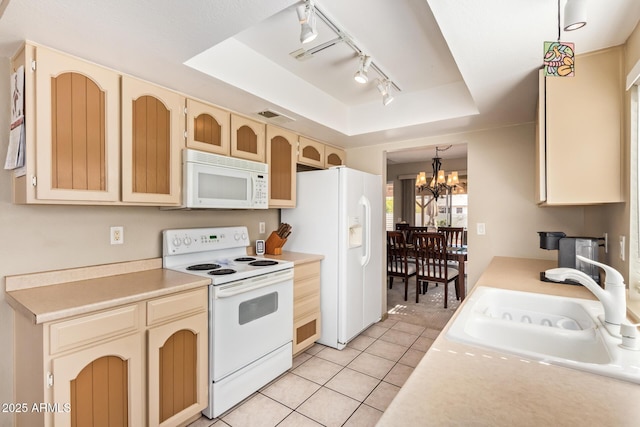 kitchen with a tray ceiling, light tile patterned flooring, a notable chandelier, white appliances, and a sink