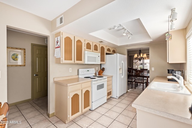 kitchen featuring white appliances, light tile patterned floors, a tray ceiling, a sink, and a chandelier