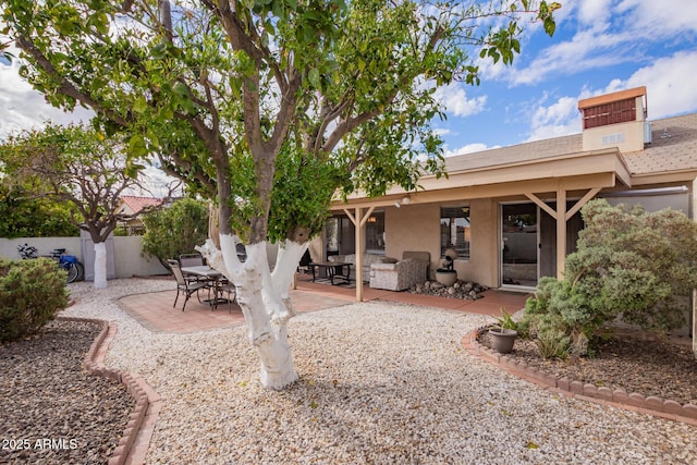 rear view of property featuring a patio, fence, and stucco siding