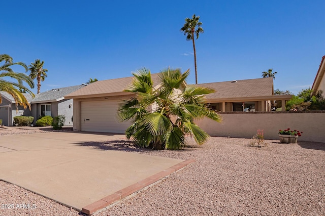 view of front facade with concrete driveway, an attached garage, fence, and stucco siding