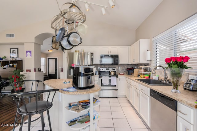 kitchen with backsplash, appliances with stainless steel finishes, white cabinetry, light tile patterned flooring, and sink