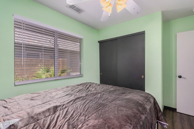 bedroom with dark hardwood / wood-style floors, a closet, and ceiling fan