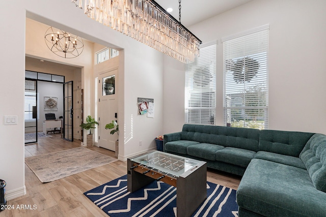 living area with a towering ceiling, baseboards, a notable chandelier, and wood finished floors