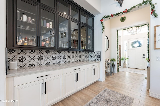 bar with tasteful backsplash, light wood-style floors, and baseboards