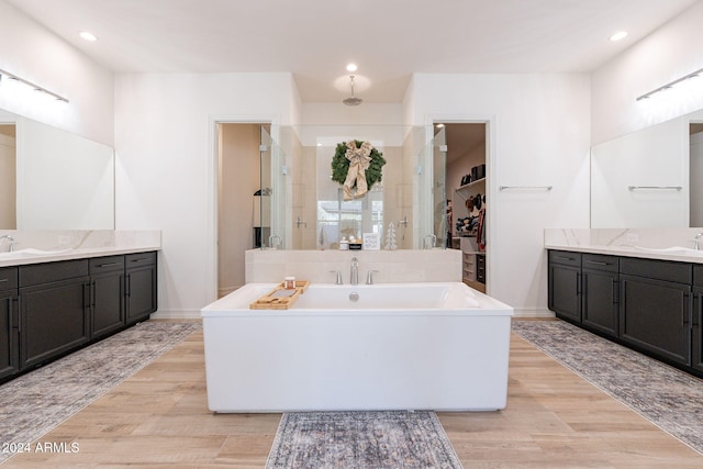 full bathroom with a stall shower, a walk in closet, recessed lighting, and wood finished floors