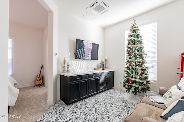 living area featuring indoor wet bar, light colored carpet, visible vents, and baseboards