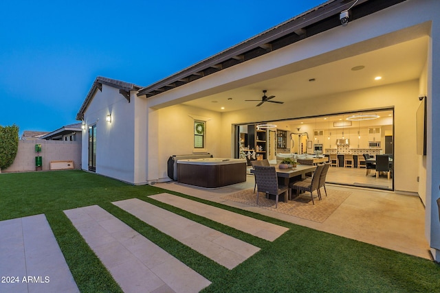 view of patio featuring ceiling fan, outdoor dining space, fence, and a hot tub