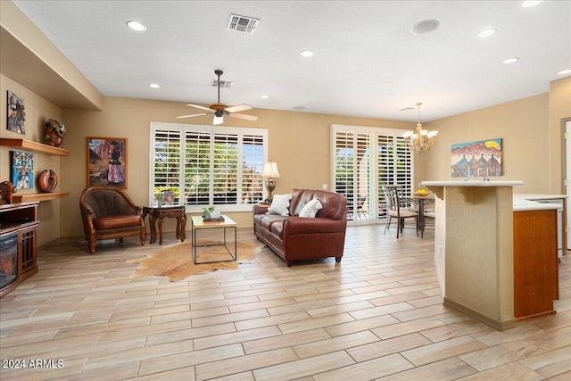 living room with ceiling fan with notable chandelier and light hardwood / wood-style flooring