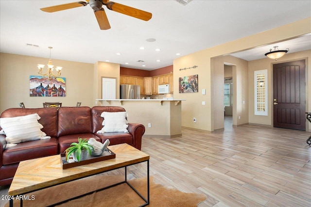 living room featuring light wood-type flooring and ceiling fan with notable chandelier