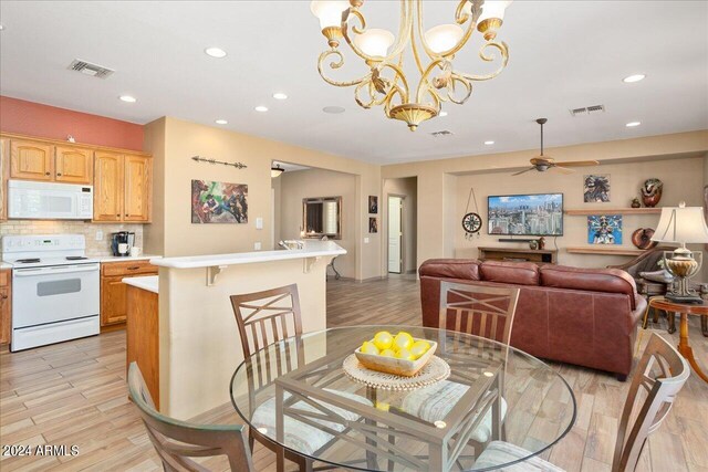 dining area featuring light wood-type flooring and ceiling fan with notable chandelier