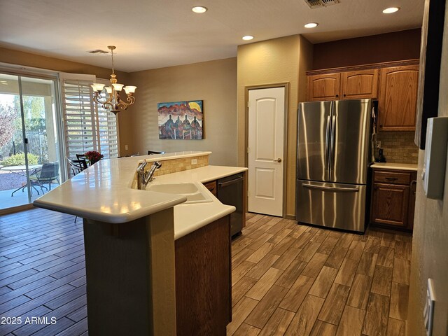 kitchen featuring white appliances, hanging light fixtures, a notable chandelier, and light hardwood / wood-style flooring