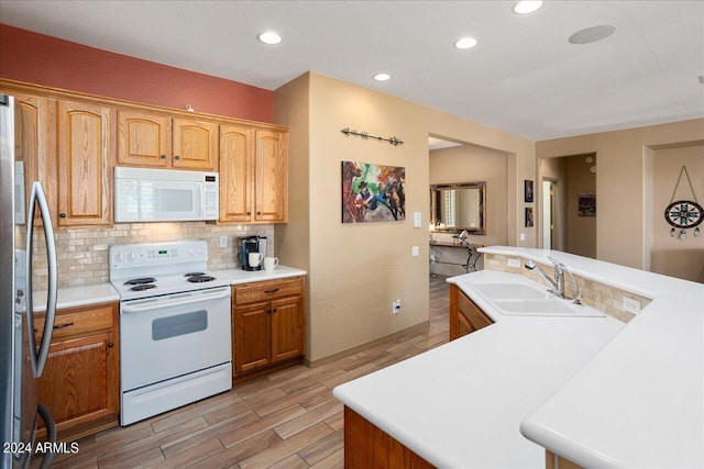 kitchen featuring light hardwood / wood-style flooring, decorative backsplash, sink, white appliances, and a center island