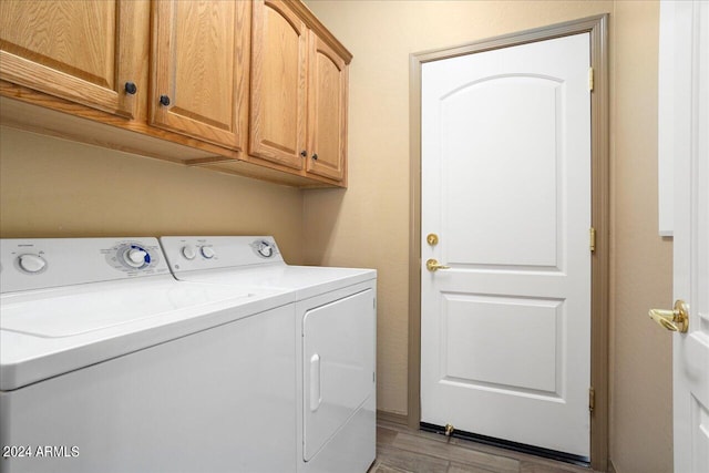 laundry room featuring washing machine and dryer, cabinets, and light hardwood / wood-style flooring