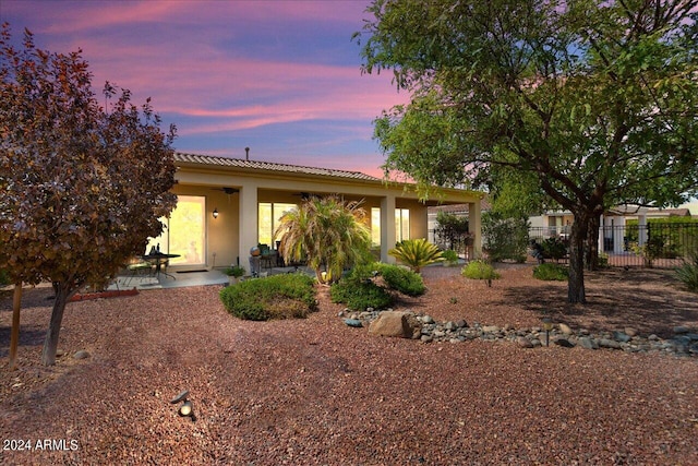 back house at dusk featuring a patio