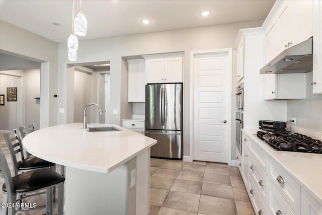 kitchen with a breakfast bar, stainless steel appliances, white cabinetry, and sink