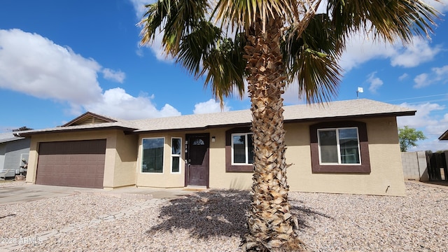 ranch-style house featuring stucco siding, a garage, concrete driveway, and fence