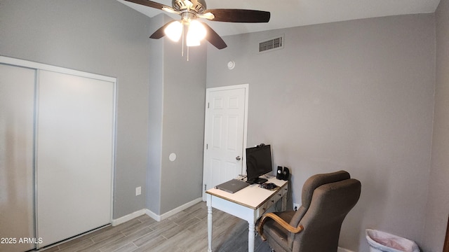 office space with light wood-type flooring, visible vents, lofted ceiling, baseboards, and ceiling fan