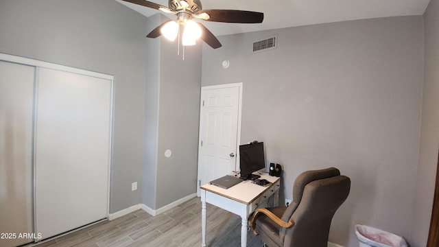 home office with visible vents, baseboards, light wood-type flooring, lofted ceiling, and a ceiling fan